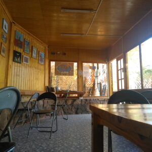 Sala de uso comum do Hostal Sonchek, com mesas, cadeiras e paredes de madeira