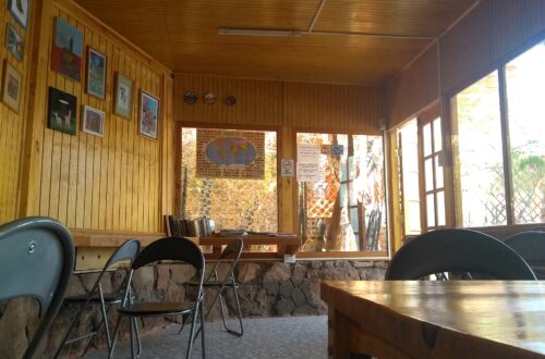 Sala de uso comum do Hostal Sonchek, com mesas, cadeiras e paredes de madeira