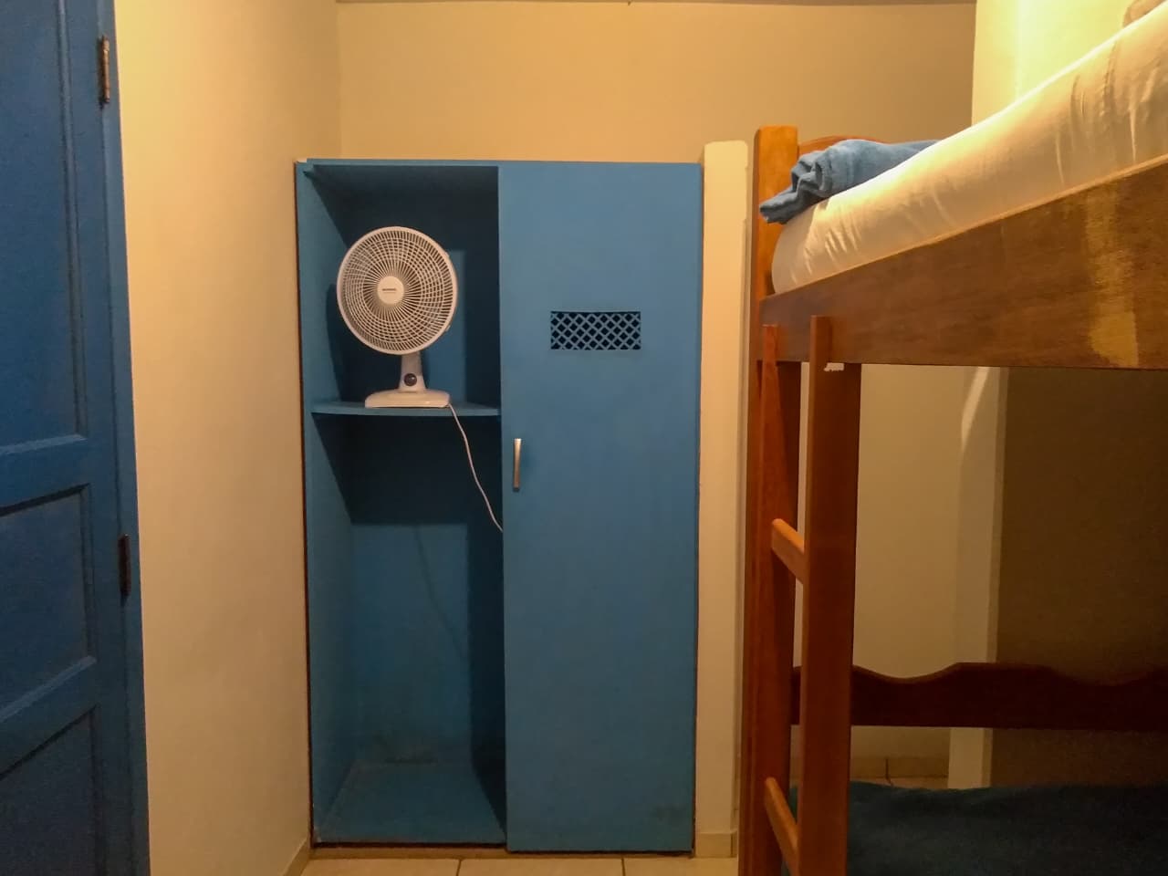 Armário e ventilador no quarto com duas camas de solteiro