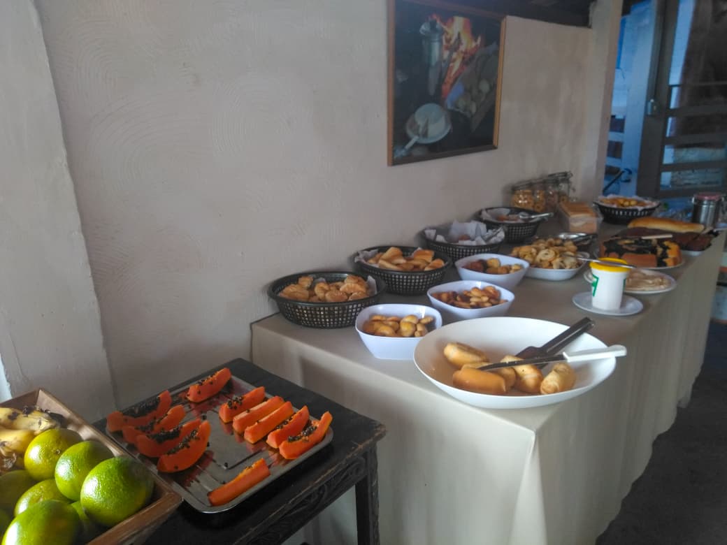 Mesa de café da manhã na pousada, com frutas, pães e bolos