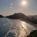 Pôr do Sol no Mirante das Galhetas, no Guarujá. Montanhas emolduram a orla ao fundo, com o mar tomando boa parte da foto