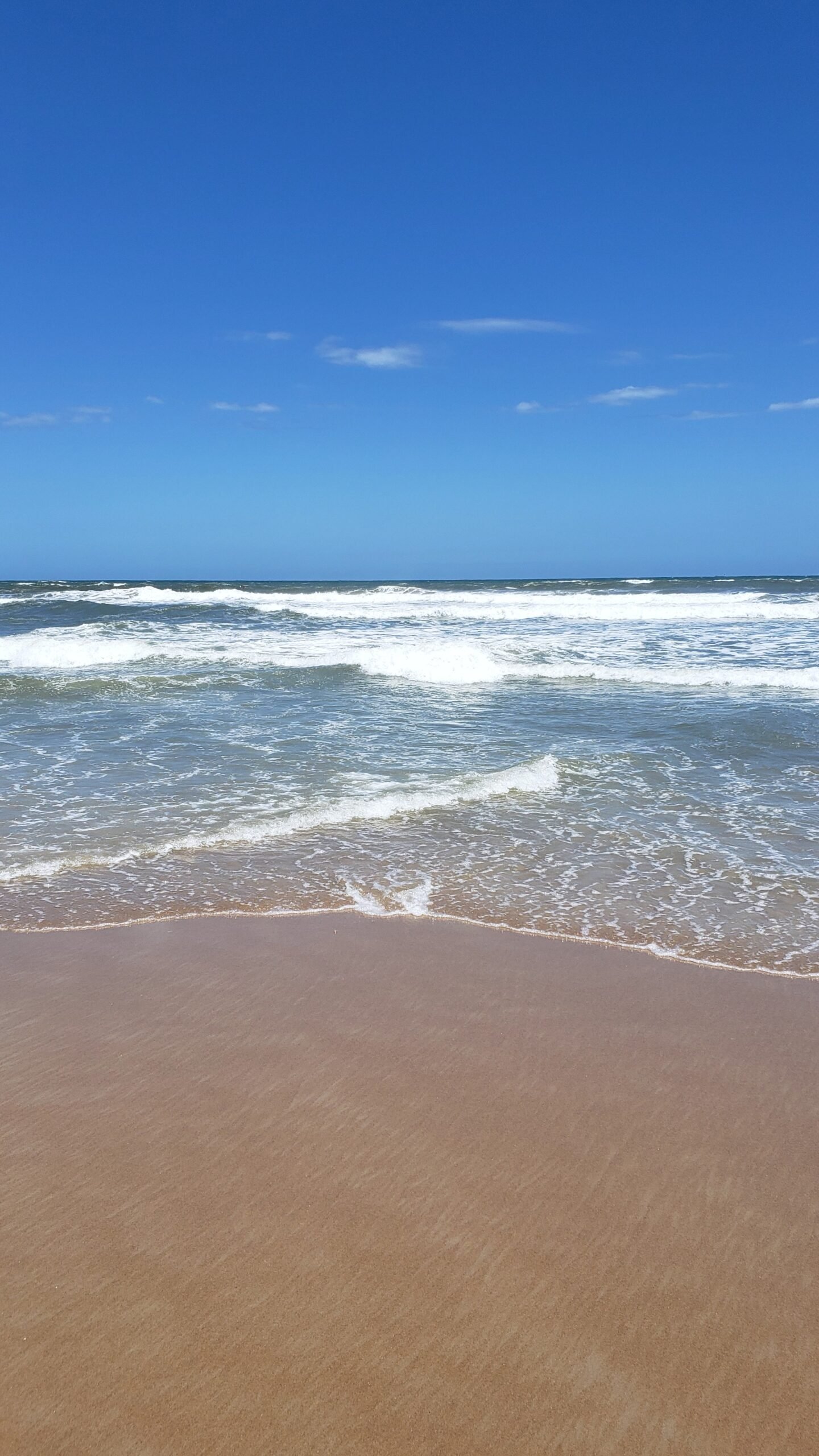 Mar da Praia do Tombo, no Guarujá, com céu azul no fundo
